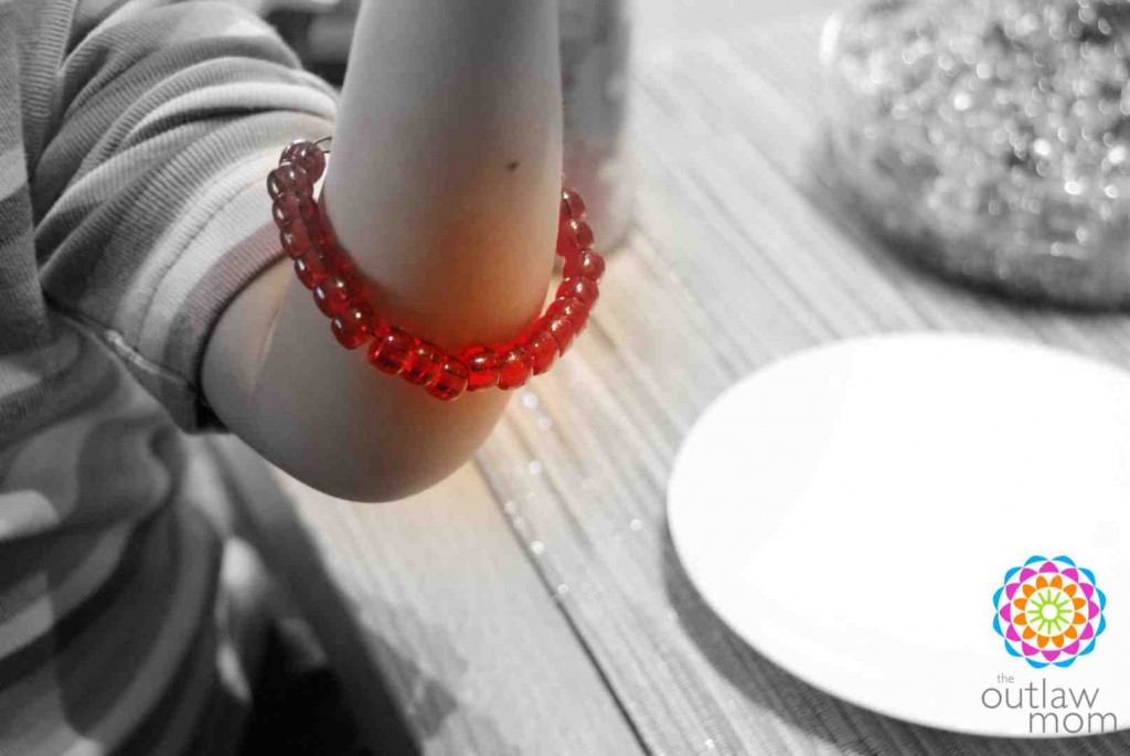 preschooler learning to make bead bracelets