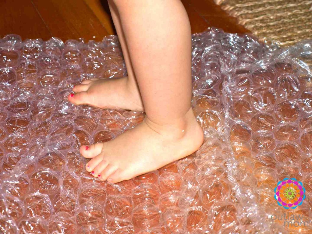 sensory-play-for-feet-walking-on-bubble-wrap child's feet standing on bubble wrap